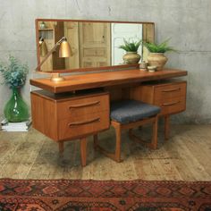 a desk with a mirror and two drawers on top of it next to a rug