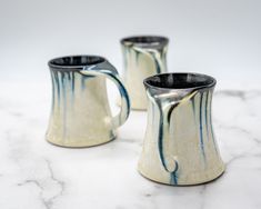 two white and blue mugs sitting on top of a marble counter