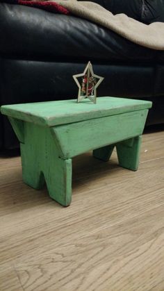 a small wooden table with a star decoration on it's top sitting on the floor in front of a black leather couch