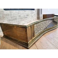 an ornate wooden box sitting on top of a hard wood floor next to a brick wall