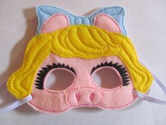 a pink mask with blonde hair and blue eyes is shown on a white tablecloth