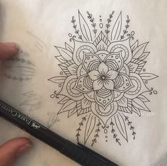 someone is drawing a flower design on a piece of paper with a marker and pen