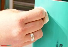 a person holding onto a blue book with their hand on the cover and ring in front of them