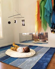 a baby is laying on a pillow in the middle of a room with clothes hanging above it