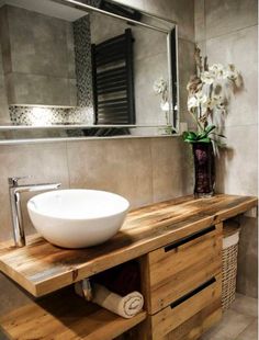 a white bowl sitting on top of a wooden counter in front of a bathroom mirror