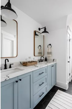 a bathroom with two sinks, mirrors and lights on the wall next to each other