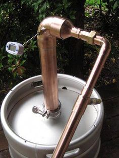 a copper colored water heater is shown in front of some trees and bushes with a digital thermometer on it