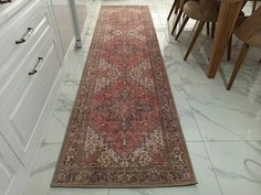 a long rug is on the floor in a room with white cabinets and wooden chairs