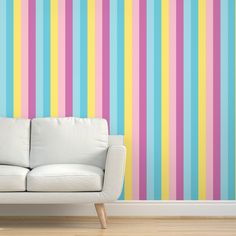 a white couch sitting in front of a colorful striped wall