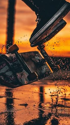 a skateboarder is falling off his board into the water as the sun sets