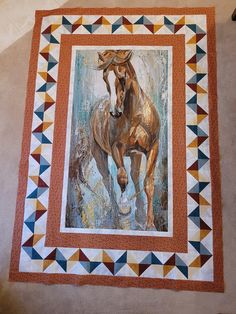 a painting of a horse running in the wind on a quilted wall hanging from a door