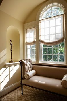 the sun shines through two large windows into a room with a couch and window sill