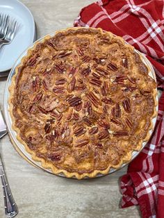 a pecan pie sitting on top of a table next to a fork and knife