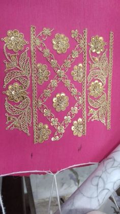 a pink pillow with gold embroidered designs on it