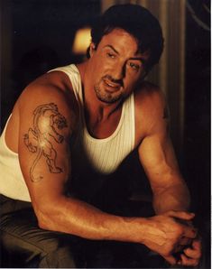 a man with a tattoo on his arm leaning over a table and looking at the camera