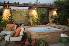 an outdoor hot tub surrounded by furniture and flowers