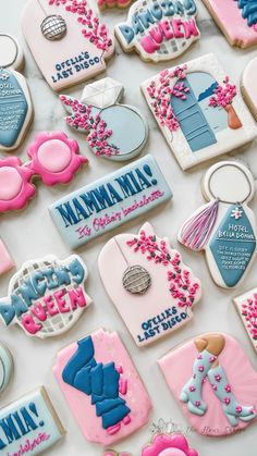 many decorated cookies are displayed on a white counter top with pink and blue frosting