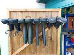 several pairs of boots hanging on a wooden wall next to other items in a storage area