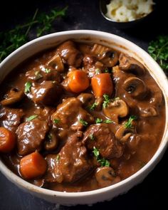 a white bowl filled with stew and carrots on top of a black countertop