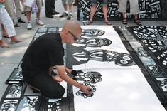 a man sitting on top of a white and black table covered in paper cut outs