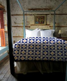 a bed with blue and white bedspread in a bedroom next to a window