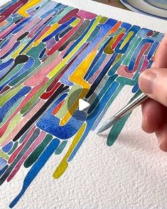 someone is drawing on paper with colored paint