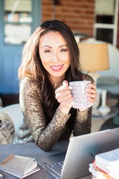 a woman sitting at a table holding a coffee cup