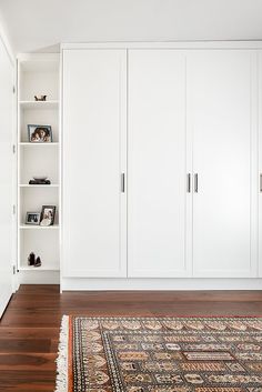 a large white bookcase in the corner of a room with wooden floors and an area rug