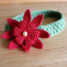 a crocheted headband with a red flower and pearl bead on it