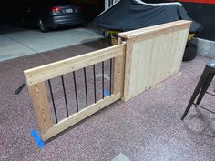 a wooden gate that is next to some chairs and a car parked in the garage