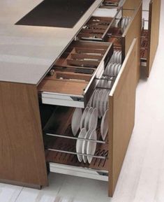 an open drawer in the middle of a kitchen with plates and utensils inside