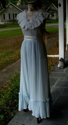 "This lovely Gunne Sax sundress was probably manufactured during the late 70s due to the gold label being of smaller proportions with the size tag sewn onto it's bottom. Not only is this a difficult to find size 11 but it has never been worn and still has the 'hang tag' attached. It has a 'Victorian' lilt to it in the triple ruffled collar but is not paired with the high neck and modest long sleeves of that design era. The main fabric is a light, linear textured voile in the lightest of sky blue Vintage Flowy Dresses For Daywear, Flowy Vintage Dresses For Daywear, Vintage Sleeveless Maxi Dress For Garden Party, Full-length Dresses For Vintage Events, Full Length Dresses For Vintage Events, Vintage Evening Dress With Empire Waist, 1970s Style Dresses For Vintage Events In Spring, Blue Lined Vintage Dress For Summer, 1970s Style Dresses For Spring Vintage Events