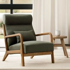 a green chair sitting in front of a window next to a table with a cup on it