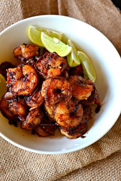 a white bowl filled with shrimp and lime wedges