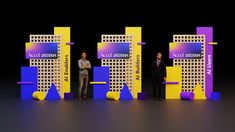 three men standing on stage in front of two tall yellow and purple signs with words