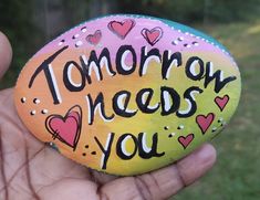 someone is holding up a painted rock that says tomorrow needs you with hearts on it