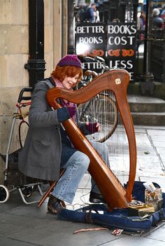 a woman sitting on the ground playing a harp