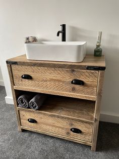 a bathroom sink sitting on top of a wooden cabinet next to a white bowl and black faucet