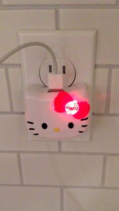 a hello kitty light is attached to a white brick wall with a red heart on it