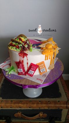 a cake that is sitting on top of a table in front of a suitcase with some food on it