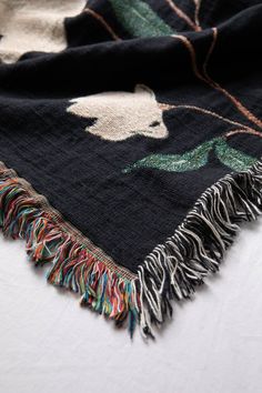 a black blanket with an animal design on it and fringes hanging from the edge