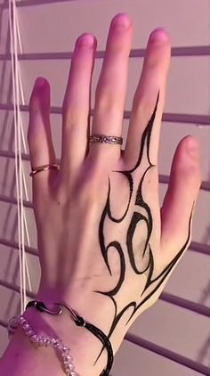 a woman's hand with black and white tattoos on her left arm, next to blinds