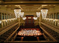 an overhead view of a large concert hall with chandeliers and orchestra on the stage