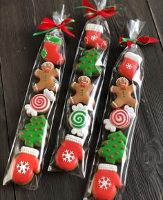 three christmas cookies in cellophane bags on top of a wooden table with candy canes