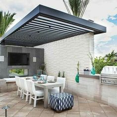 an outdoor tv sitting on top of a patio next to a table with chairs and a grill