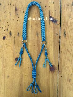 a blue rope with tassels is on a wooden surface and has two hooks attached to it