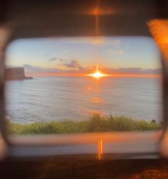 the sun is setting over the ocean as seen through a window