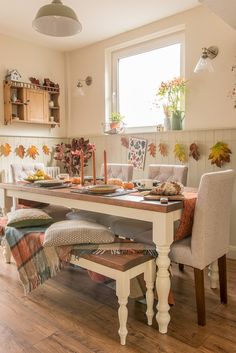 a dining room table and chairs with fall leaves on the wall