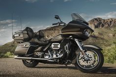 a black and brown motorcycle parked on the side of a road in front of mountains