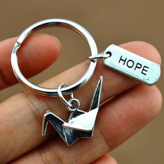 a hand holding a metal keychain with the word hope on it